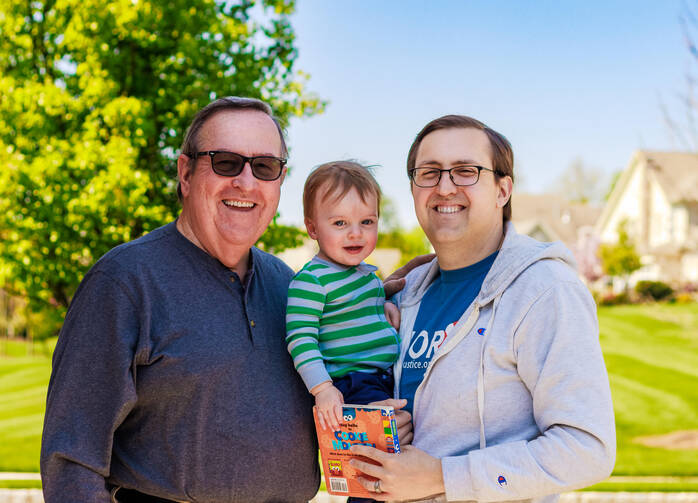 The author, his father and his infant son outdoors in front of a tree.