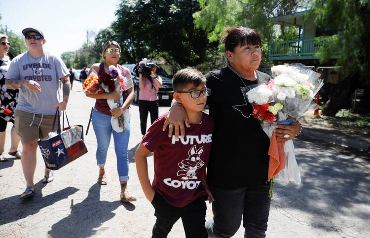 Dora Flores and her grandson arrive at Robb Elementary School in Uvalde, Texas, May 25, 2022, with flowers the day after a mass shooting. (CNS photo/Marco Bello, Reuters)