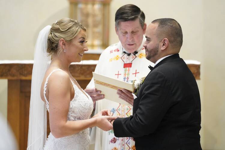Christina MacDougall places a wedding band on Julio Prendergast's finger as Msgr. Francis J. Schneider officiates their wedding Mass Aug. 20, 2021, at St. John the Baptist Church in Wading River, N.Y. (CNS photo/Gregory A. Shemitz)