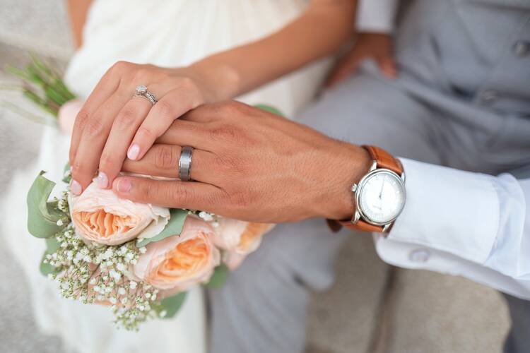 Close-up of a bride and groom holding hands on their wedding day.