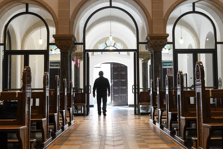 With empty pews on his right and left, a man walks away, towards the open doors of the church