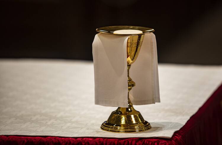 The Eucharist rests on a golden paten, stacked atop a golden chalice, upon the altar