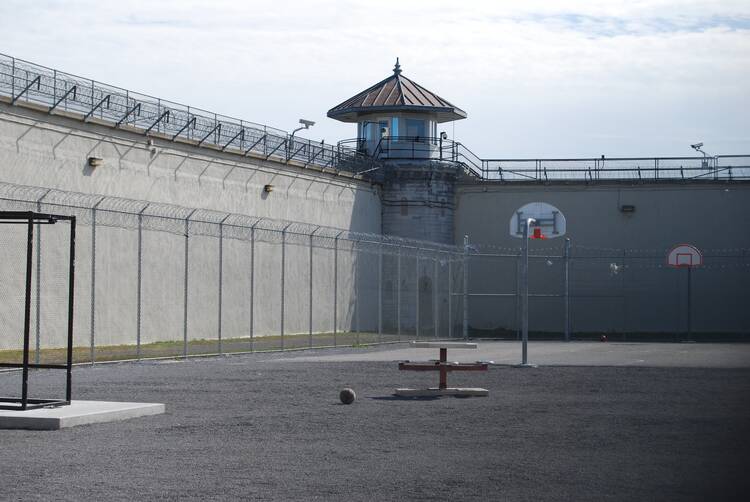 A basketball court in a concrete yard, surrounding by a prison building