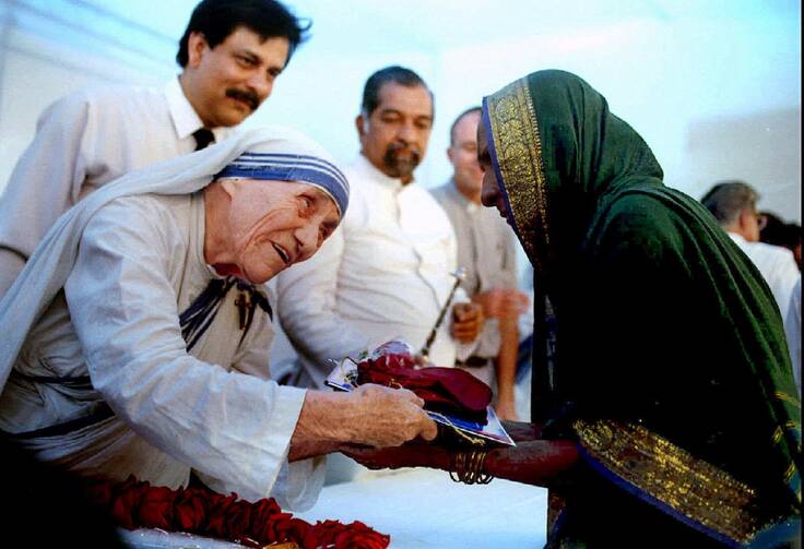 Mother Teresa presents documents for a new house to a villager.