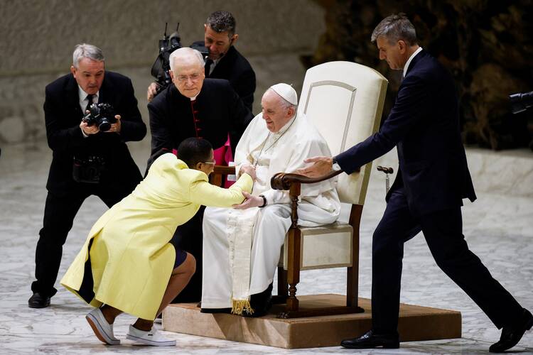 A woman kneels before Pope Francis during the weekly general audience at the Vatican.