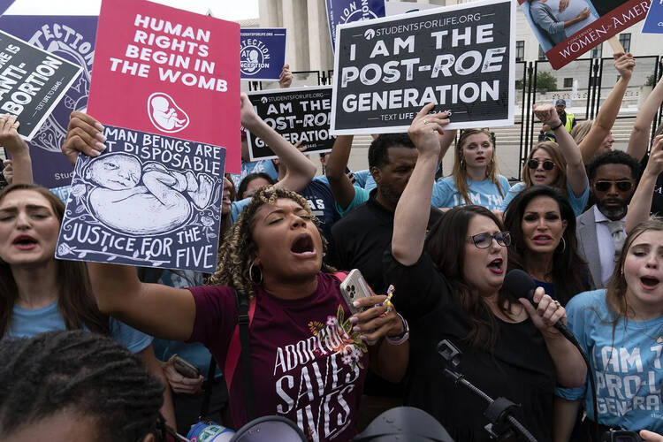 women stand outside supreme court shouting, holding pro-life signs, I am the post-roe generation. woman center is a person of color