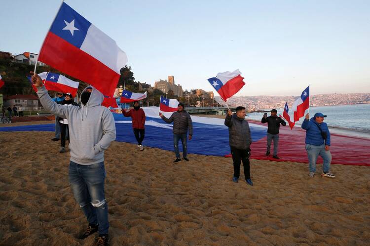 People hold Chilean flags on a beach during a rally in opposition to a proposed new constitution.