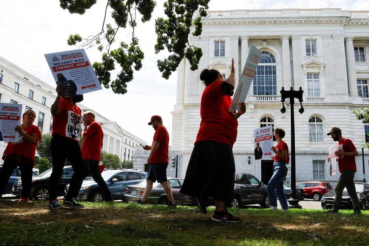 A group marches holding signs calling for new labor contracts.