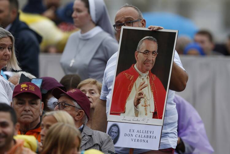 A man holds a photo of Pope John Paul I prior to Pope Francis' celebration of the beatification of Pope John Paul I in St. Peter's Square at the Vatican Sept. 4, 2022. (CNS photo/Paul Haring)