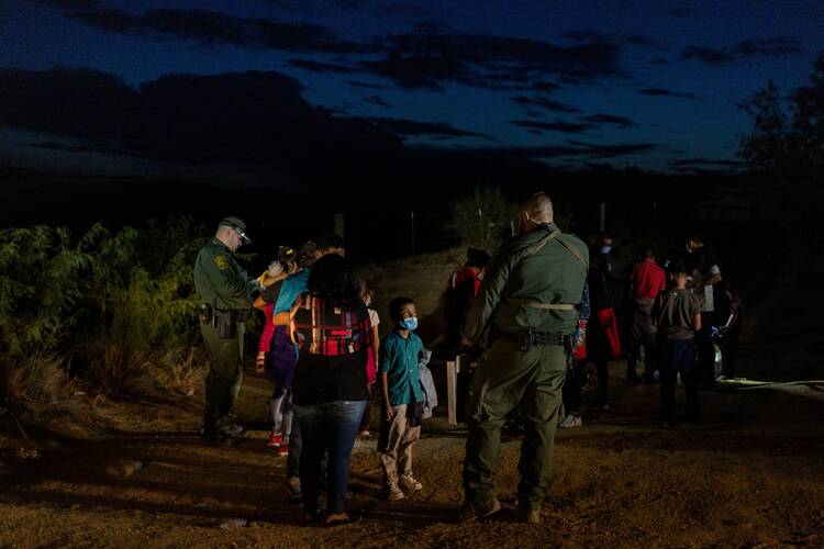 Jefferson, an 8-year old boy from Honduras, stands near his parents as he is questioned by a border patrol agent Aug. 26, 2022, after they smuggled across the Rio Grande into Roma, Texas. (CNS photo/Adrees Latif, Reuters)
