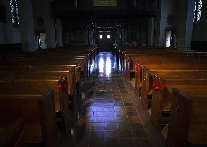 A photo of an empty church with rows of empty pews.
