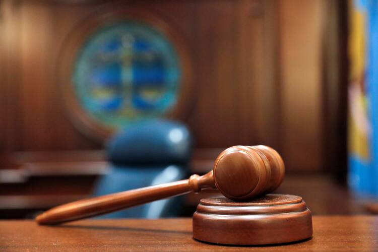 a court gavel in focus with wood wall and glass window behind it