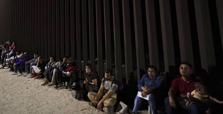 Migrants wait to be processed by Border Patrol after crossing into the United States near Yuma, Ariz., on Aug. 23. (AP Photo/Gregory Bull)