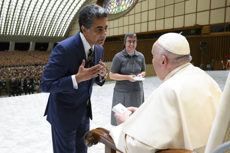 A man in a blue suit bows to Pope Francis, with a sister in her habit standing to his left