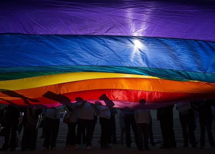 In this 2015 file photo, LGBTQ supporters wave a flag outside the U.S. Supreme Court in Washington. The Catholic Medical Association joined a lawsuit Aug. 26, 2021, challenging the U.S. Department of Health and Human Services' mandate that doctors and hospitals must perform gender-transition procedures over their own moral or medical objections. (CNS photo/Tyler Orsburn)