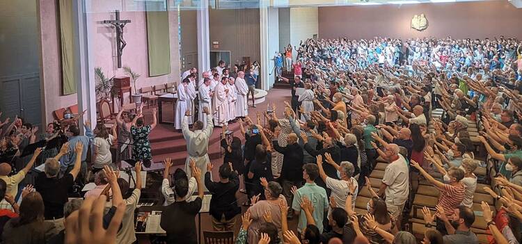 Parishioners hold up their hands in a blessing at the final Mass celebrated by the Paulists at Ohio State, July 31 (photo: ) 