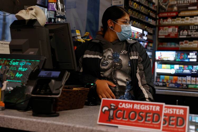 a pregnant woman stands behind a cash register counter that has a sign reading closed in front of it