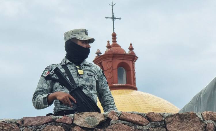A member of the Mexican army stands guard outside St. Francisco Javier church in Cerocahui on June 22, 2022. Jesuit Fathers Javier Campos Morales and Joaquín César Mora Salazar were murdered at the parish on June 20 as they offered refuge to a tour guide seeking protection. (CNS photo/Reuters)