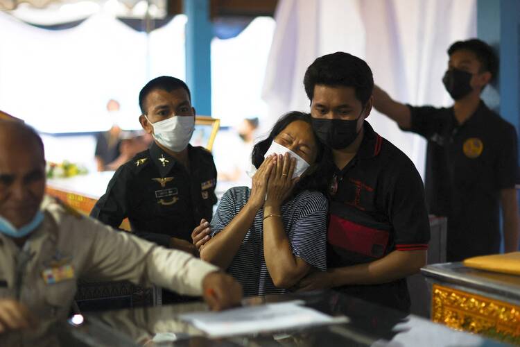 A woman reacts after identifying the body of a loved one at Sri Uthai temple in Na Klang, Thailand.