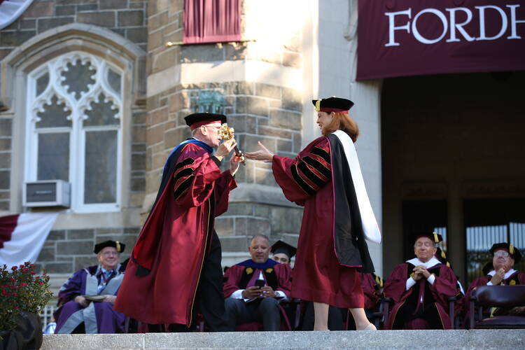 Father Joseph M. McShane, S.J. passes the ceremonial university mace to Tania Tetlow during her inauguration ceremony on October 14, 2022. Photo by Bruce Gilbert/Fordham University.