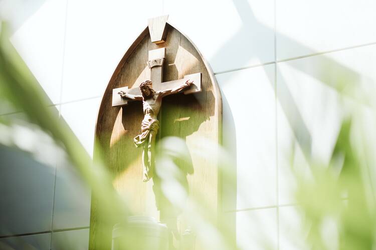 crucifix on a wall behind some out of focus green grass in front