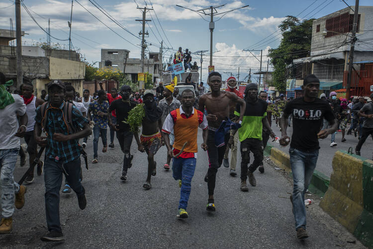 Protesters calling for the resignation of Haitian Prime Minister Ariel Henry run after police fired tear gas to disperse them in the Delmas area of Port-au-Prince, Haiti, Monday, Oct. 10, 2022. (AP Photo/Odelyn Joseph)