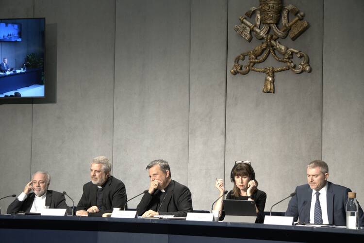 giacomo costa, piero coda, mario grech, anna rowlands, matteo bruni sitting at a table with the vatican seal behind them