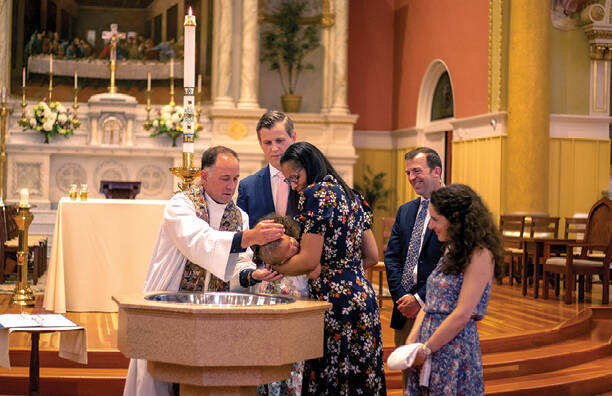 The Rev. John Unni baptizes Natasha and Jan Hartman’s daughter at St. Cecilia Church in Boston, Mass. (photo: America Media)