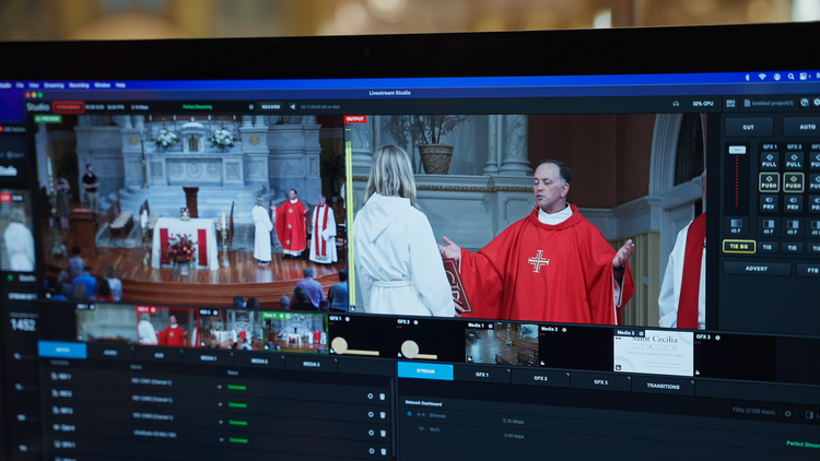 father john unni gives a homily on the screen of a computer