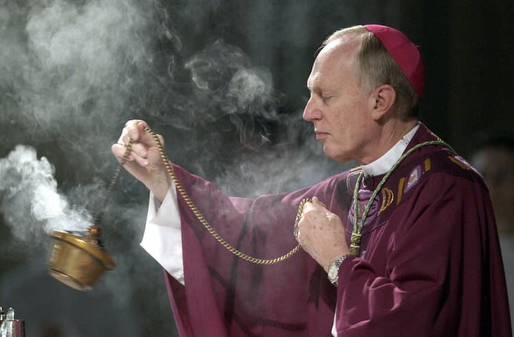 A man in red robes and a bishop's hat swings incense in a gold burner