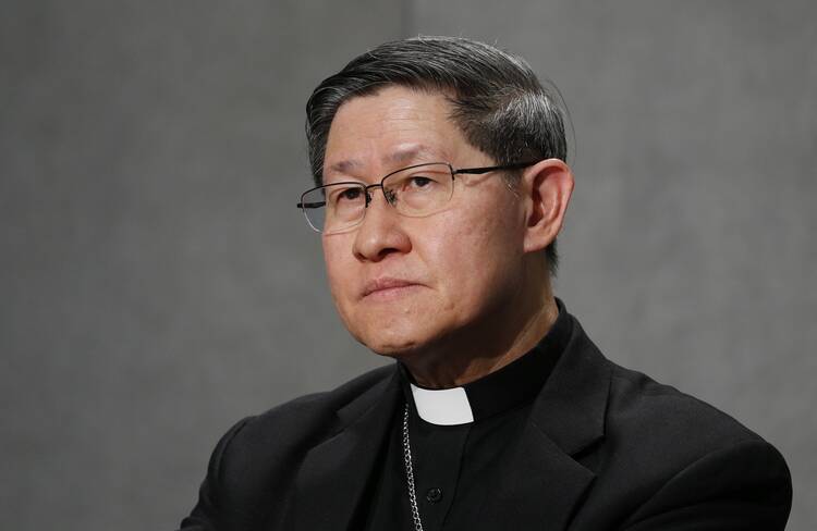 cardinal luis antonio tagle sits with a gray background behind him while wearing his clerics