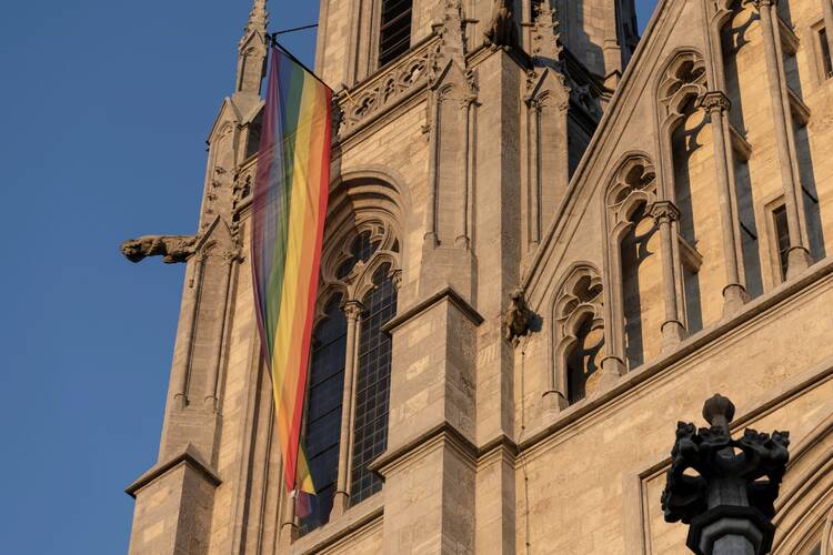 A rainbow flag hangs off of a Gothic church
