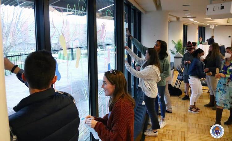 A group of young adults draw on windows with markers