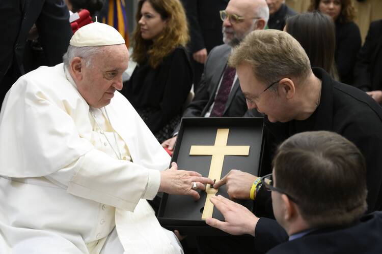pope francis touches a cross held by another man