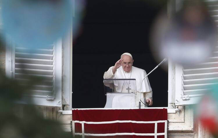 Pope Francis is framed by decorations on the Christmas tree as he leads the Angelus from the window of his studio overlooking St. Peter's Square at the Vatican.