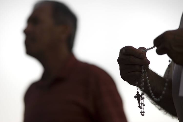 An attendee prays the rosary Oct. 1, 2018, during a public session on the issue of clergy sexual abuse at Our Mother of Confidence Parish Hall in San Diego. (CNS photo/David Maung)