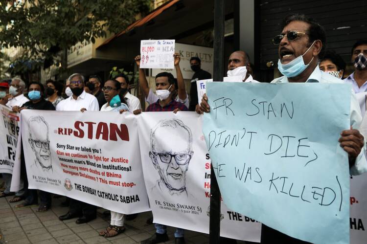 People hold a banner during a prayer service for Jesuit Father Stan Swamy.