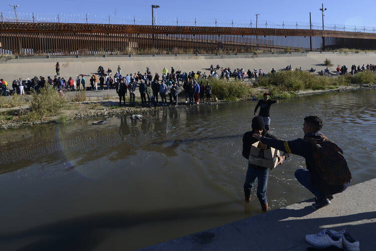 Migrants cross the Mexico-U.S. border to surrender to U.S. Border Patrol agents from Ciudad Juarez, Mexico, on Dec. 12. According to the Ciudad Juarez Human Rights Office, hundreds of mostly Central American migrants arrived in buses and crossed the border to seek asylum in the U.S., after spending the night in shelters. (AP Photo/Christian Chavez)