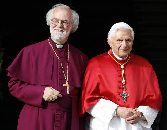 rowan williams stands at left and pope benedict at right, both wear red vestments and smiles