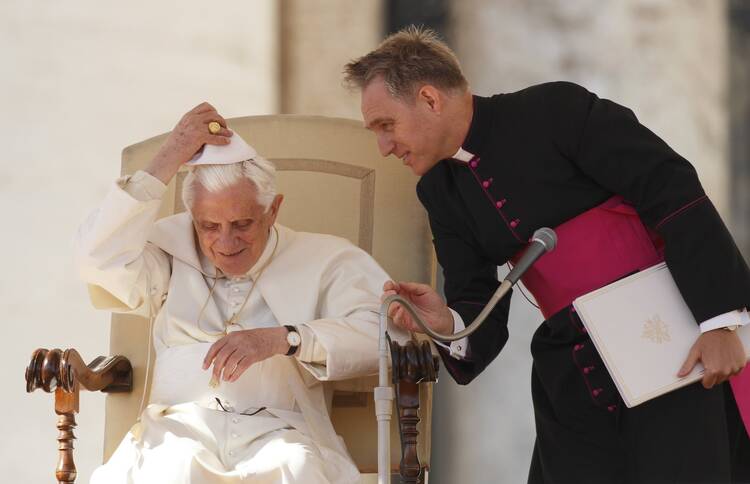 Pope Benedict XVI replaces his zucchetto after a wind gust as his personal secretary, Msgr. Georg Ganswein, assists during the pontiff's general audience in St. Peter's Square at the Vatican in this Oct. 27, 2010 file photo. Archbishop Gänswein has written a book about his life with the late pope and his own difficult relationship with Pope Francis. (CNS photo/Paul Haring)