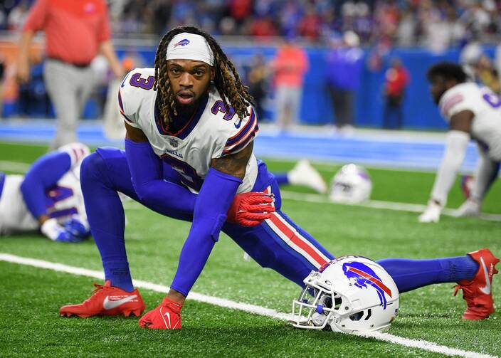 A football player in blue leggings stretches on a football field