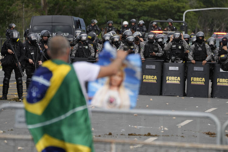 A protester, supporter of Brazil's former President Jair Bolsonaro, in confronted by a police phalanx.