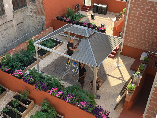 Three men put metal sheets on the roof of a shed 