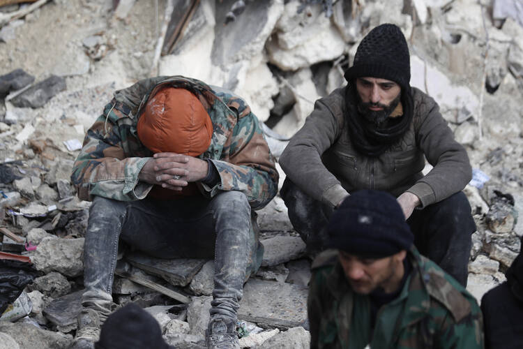 People react as they sit on the wreckage of collapsed buildings, in Aleppo, Syria, on Feb. 7, 2023. Rescuers raced to find survivors in the rubble of thousands of buildings brought down by powerful earthquake and multiple aftershocks that struck eastern Turkey and neighboring Syria. (AP Photo/Omar Sanadiki)