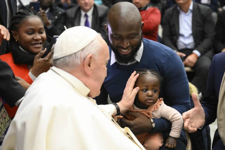 pope francis blesses a little girl in the arms of her father