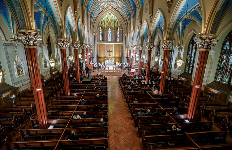 looking down at a church with gothic style architecture with about 50 people inside during a mass