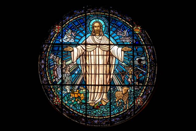 jesus stands with arms outstretched in a stained glass image