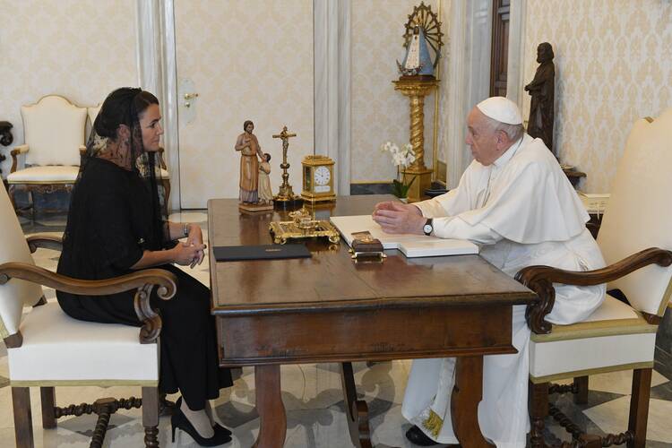 pope francis sits at right across a table from president of hungary katalin novak at left