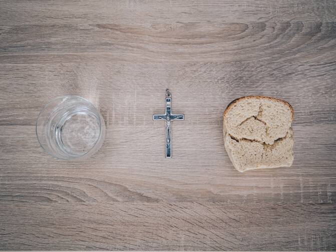 Bowl of water, crucifix and piece of bread