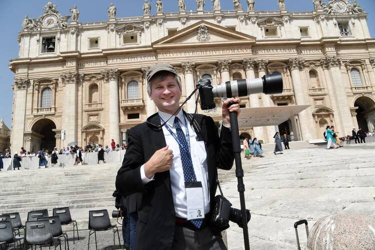 paul haring stands in front of a building in rome with a camera